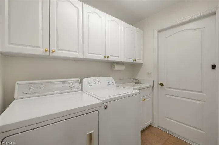 Laundry room featuring cabinets, separate washer and dryer, sink, and light tile patterned floors