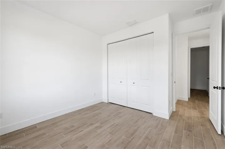 Room featuring wood-look tile flooring, white baseboards, and a bi-fold closet with black hardware