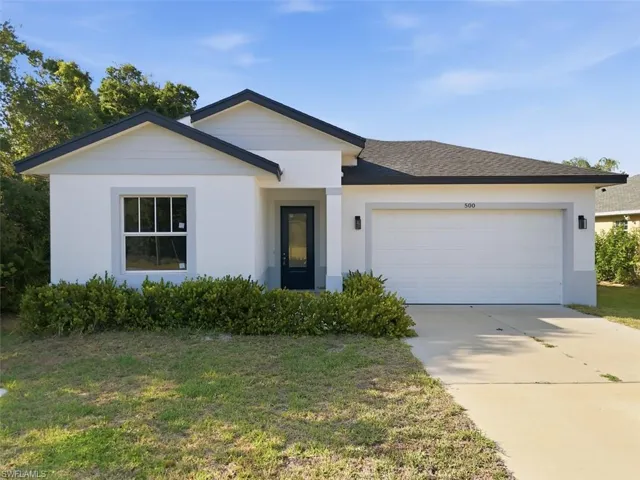Contemporary facade featuring stucco and siding accents, a dark asphalt shingle roof, a two-car garage with a concrete driveway, a dark entry door with frosted glass, and a manicured shrub border