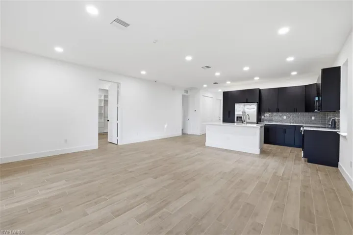 Open-concept living space featuring wood-finish flooring, recessed lighting, and a modern kitchen with dark cabinetry