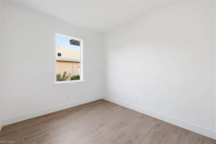 Bright room featuring a single window, white walls, and wood-finish tile flooring