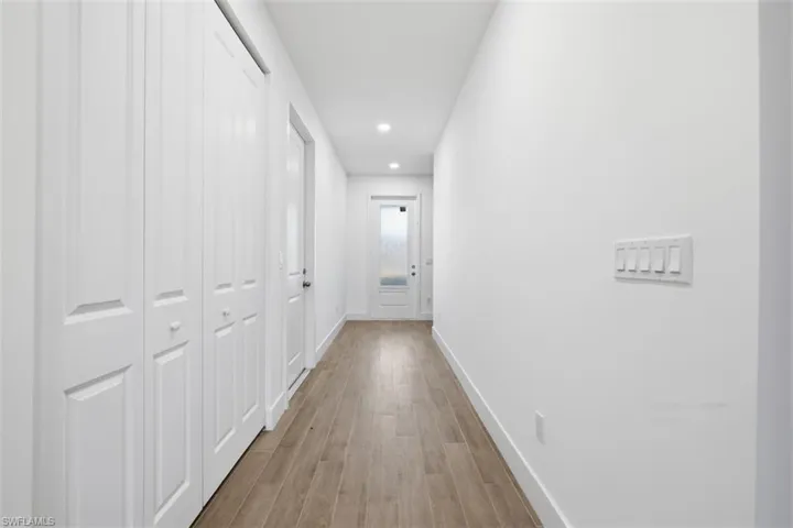 Hallway featuring wood-finish flooring, recessed lighting, and white bifold doors