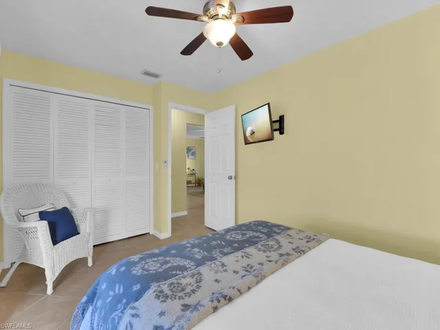 Bedroom featuring ceiling fan, tile patterned floors, and a closet