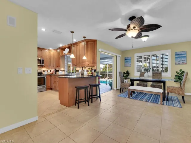 Kitchen with pendant lighting, appliances with stainless steel finishes, kitchen peninsula, light tile patterned flooring, and a breakfast bar