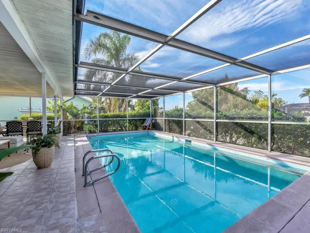 View of swimming pool featuring glass enclosure and a patio area