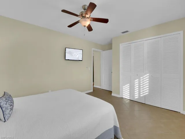 Tiled bedroom with ceiling fan and a closet
