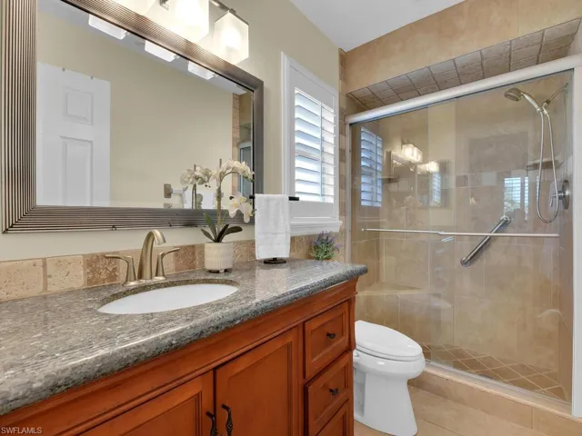 Bathroom with toilet, vanity, tile patterned floors, and a shower with shower door