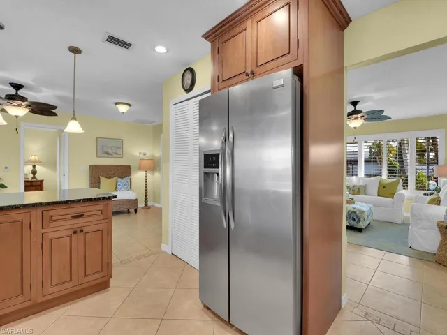 Kitchen with hanging light fixtures, light tile patterned floors, ceiling fan, and stainless steel fridge with ice dispenser