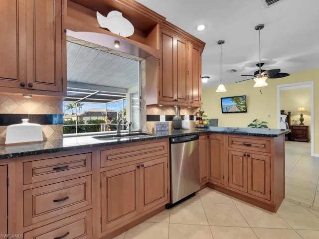 Kitchen with stainless steel dishwasher, kitchen peninsula, decorative backsplash, sink, and hanging light fixtures
