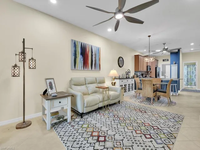 Tiled living room featuring ceiling fan with notable chandelier