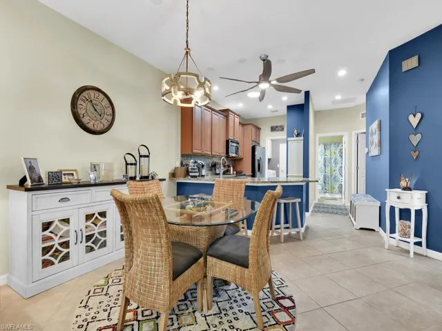 Dining area with ceiling fan with notable chandelier, light tile patterned floors, and sink