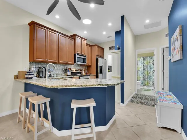 Kitchen featuring stainless steel appliances, kitchen peninsula, sink, ceiling fan, and a breakfast bar