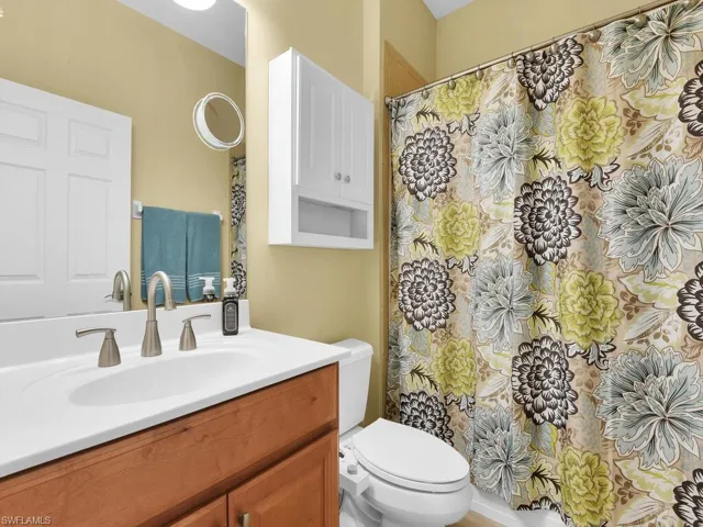 Bathroom with curtained shower, toilet, and vanity