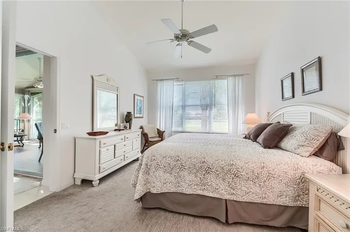Bedroom with high vaulted ceiling, light carpet, a ceiling fan, and multiple windows