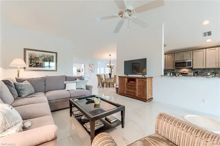 Living area with recessed lighting, visible vents, marble finish floor, and ceiling fan with notable chandelier