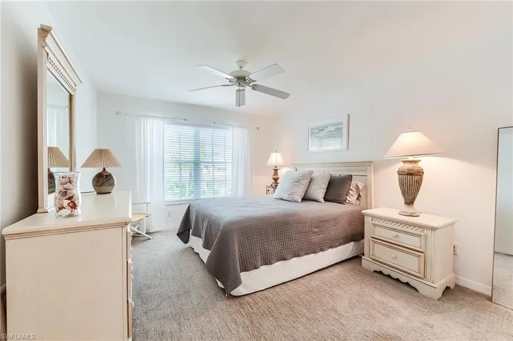 Bedroom featuring light colored carpet, ceiling fan, and baseboards