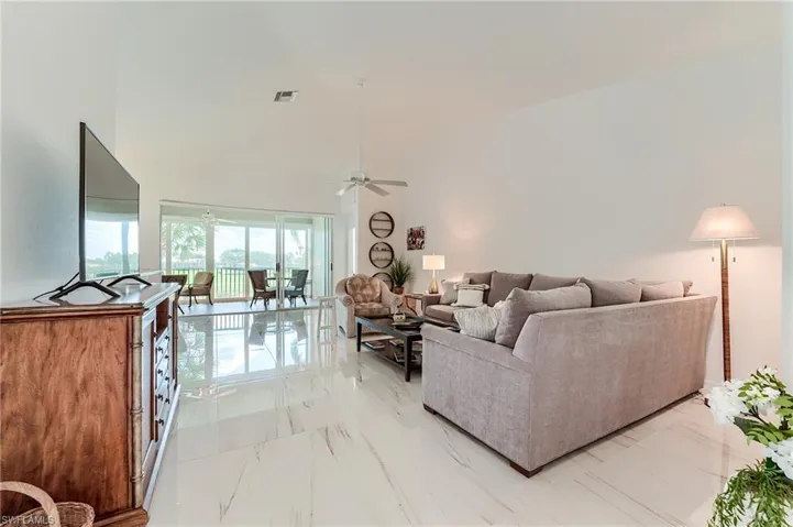 Living room featuring high vaulted ceiling, marble finish floor, ceiling fan, and visible vents