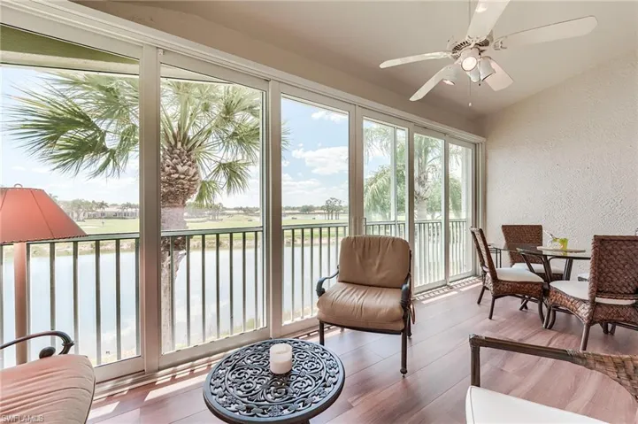 Sunroom / solarium featuring a textured wall, a water view, and wood finished floors