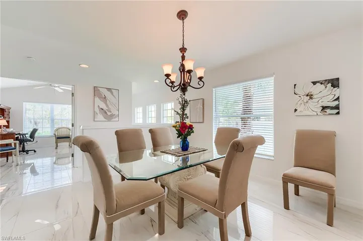 Dining room with ceiling fan with notable chandelier, baseboards, a wealth of natural light, and recessed lighting