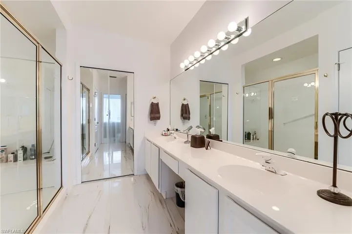 Full bathroom featuring marble finish floor, a sink, double vanity, and an enclosed shower