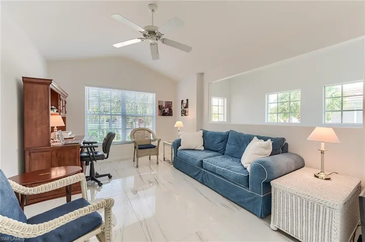 Living room featuring vaulted ceiling, marble finish floor, and ceiling fan