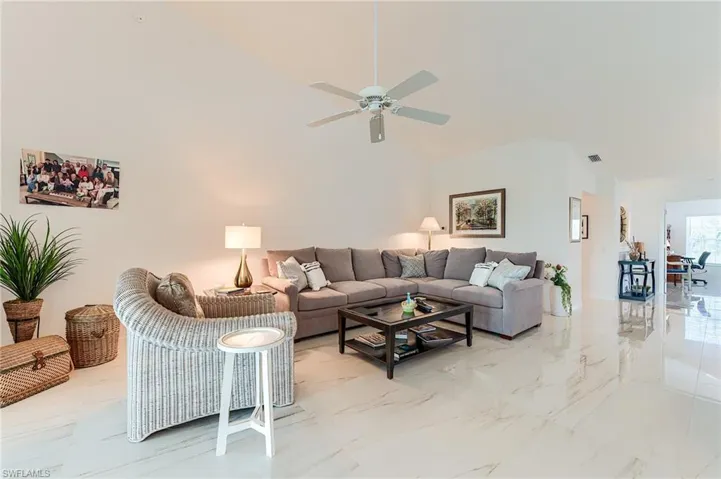 Living area featuring high vaulted ceiling, marble finish floor, a ceiling fan, and visible vents