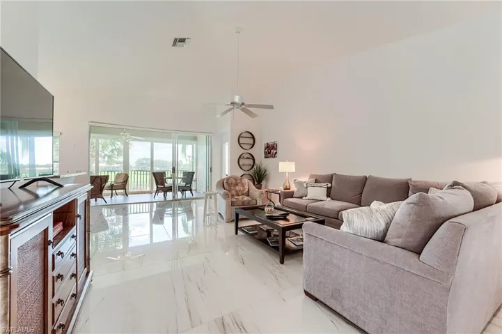 Living area with high vaulted ceiling, marble finish floor, a ceiling fan, and visible vents