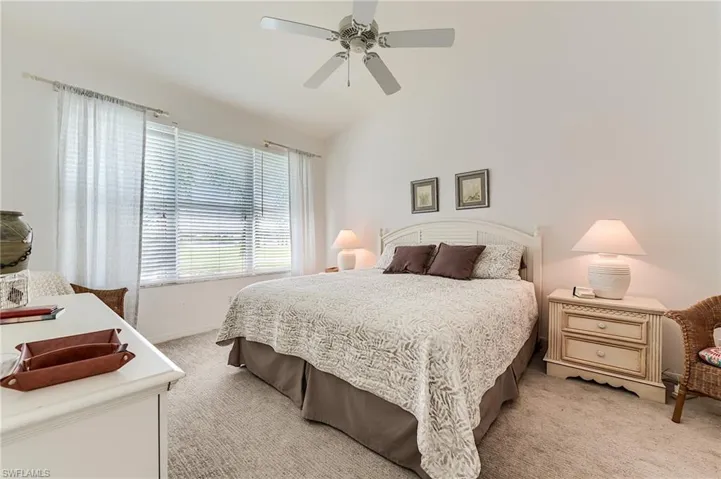 Bedroom with light colored carpet, lofted ceiling, a ceiling fan, and baseboards