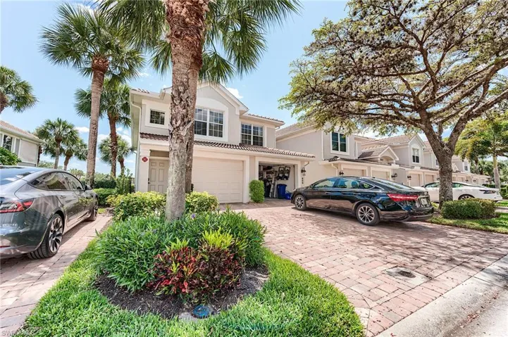 View of front of property featuring a garage, stucco siding, and decorative driveway