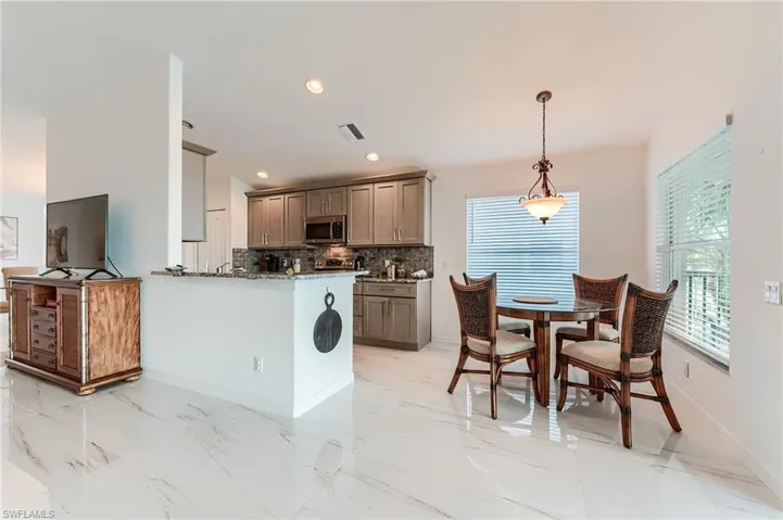 Kitchen featuring backsplash, visible vents, gray cabinets, stainless steel microwave, and baseboards