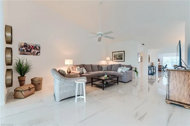 Living room with marble finish floor, vaulted ceiling, and a ceiling fan