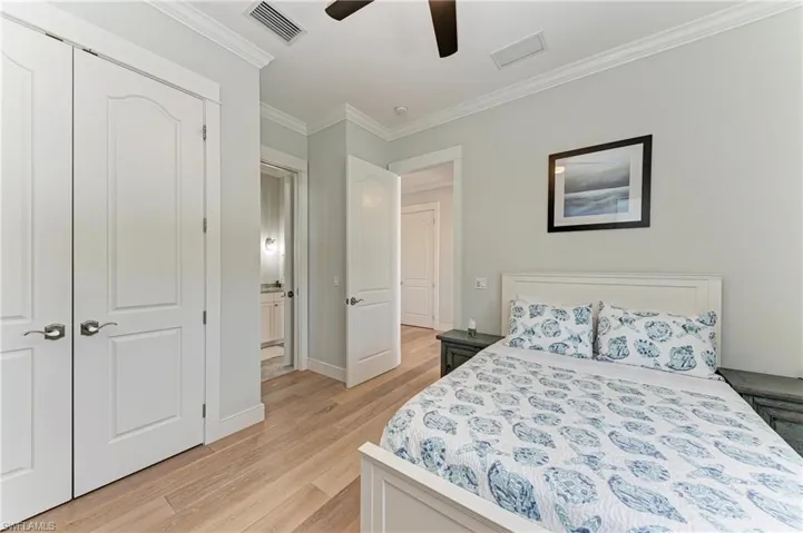 Bedroom with ornamental molding, light hardwood / wood-style floors, and ceiling fan