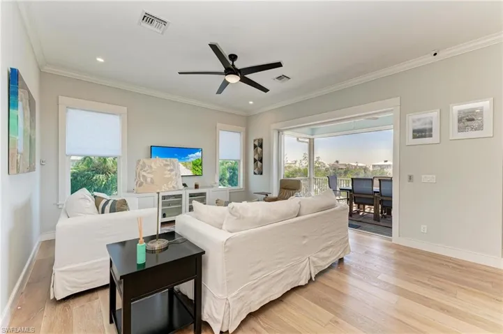 Living room featuring ceiling fan, ornamental molding, plenty of natural light, and light hardwood / wood-style floors