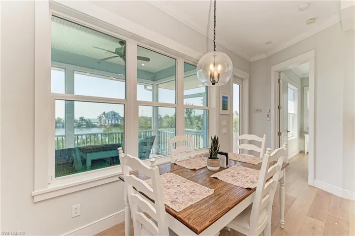 Dining room featuring ornamental molding, light hardwood / wood-style floors, ceiling fan, and a water view