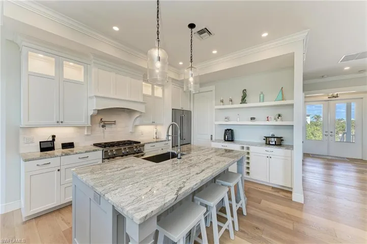 Kitchen with white cabinetry, sink, high end appliances, and a center island with sink