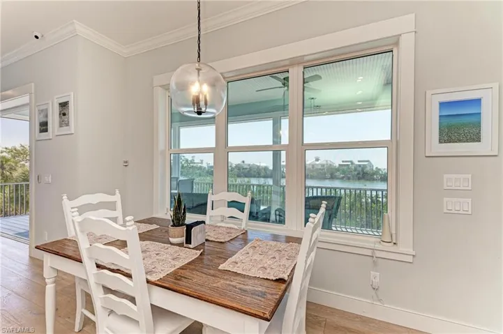 Dining space featuring a water view, ornamental molding, and light wood-type flooring