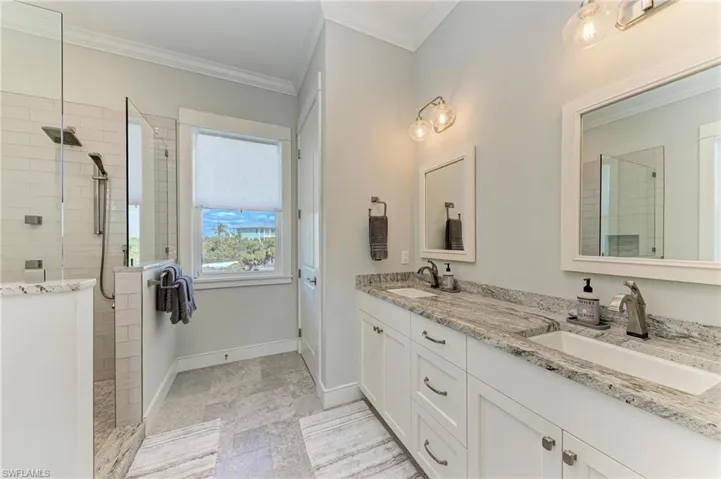 Bathroom with crown molding, tiled shower, and vanity