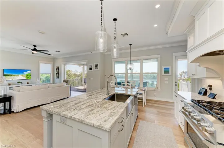 Kitchen featuring pendant lighting, white cabinetry, and a center island with sink