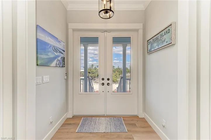 Doorway to outside with light hardwood / wood-style flooring, ornamental molding, and french doors