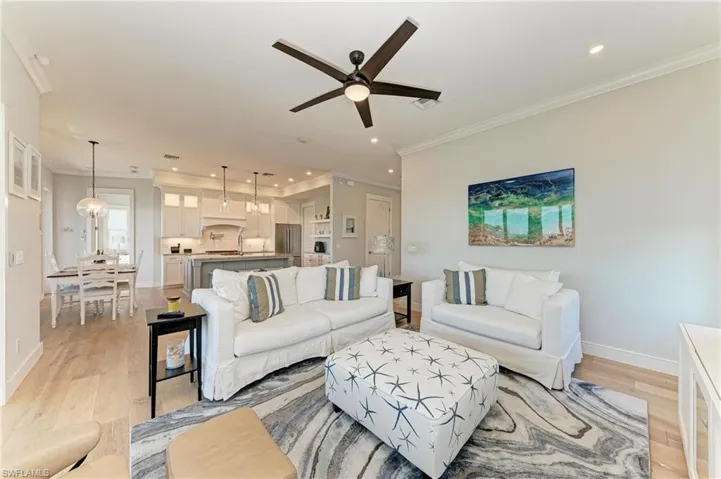 Living room featuring ceiling fan, ornamental molding, and light hardwood / wood-style flooring