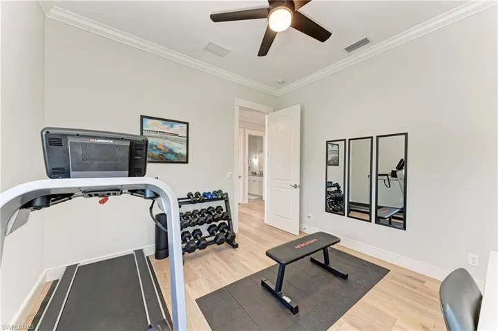 Workout area with crown molding, ceiling fan, and wood-type flooring