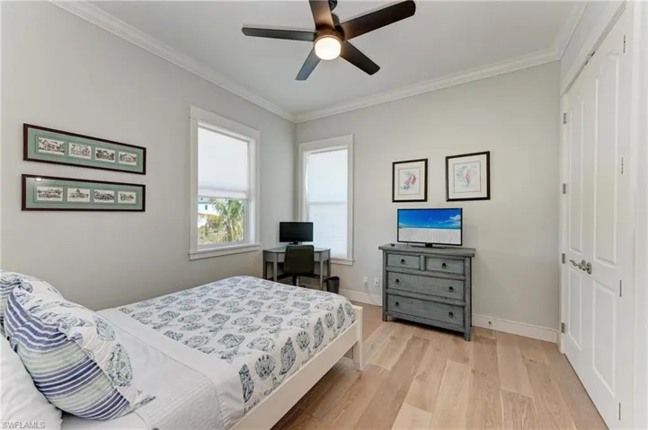 Bedroom with ornamental molding, ceiling fan, light wood-type flooring, and a closet