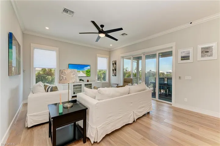 Living room featuring ceiling fan, crown molding, light hardwood / wood-style flooring, and a healthy amount of sunlight