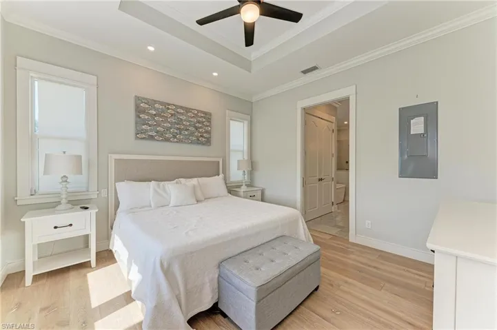 Bedroom featuring a raised ceiling, crown molding, and light hardwood / wood-style flooring