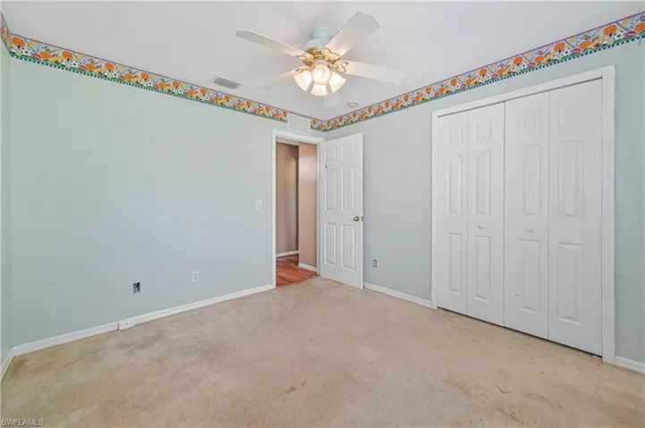 Unfurnished bedroom featuring ceiling fan, light carpet, and a closet