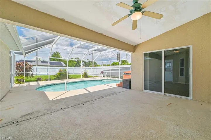 View of swimming pool featuring ceiling fan, glass enclosure, and a patio area