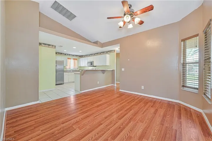 Unfurnished living room featuring ceiling fan, lofted ceiling, and light wood-like flooring