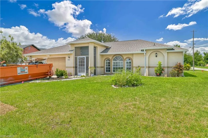 View of front facade featuring a garage and a front lawn