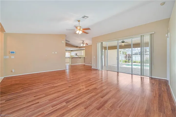 Unfurnished living room with ceiling fan, light wood-type flooring, and vaulted ceiling
