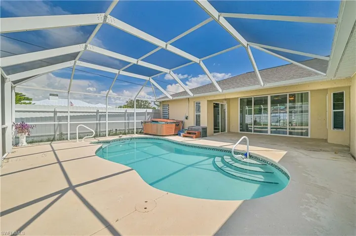 View of swimming pool with a patio, a lanai, and a hot tub
